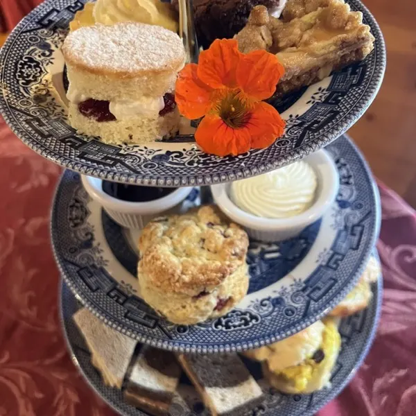 Three-tier stand of scones, cream and sweets on blue willow china