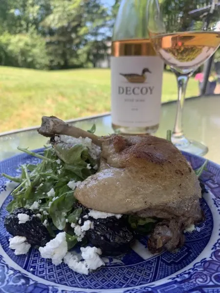 Crispy duck confit over greens and beets with a bottle of white wine