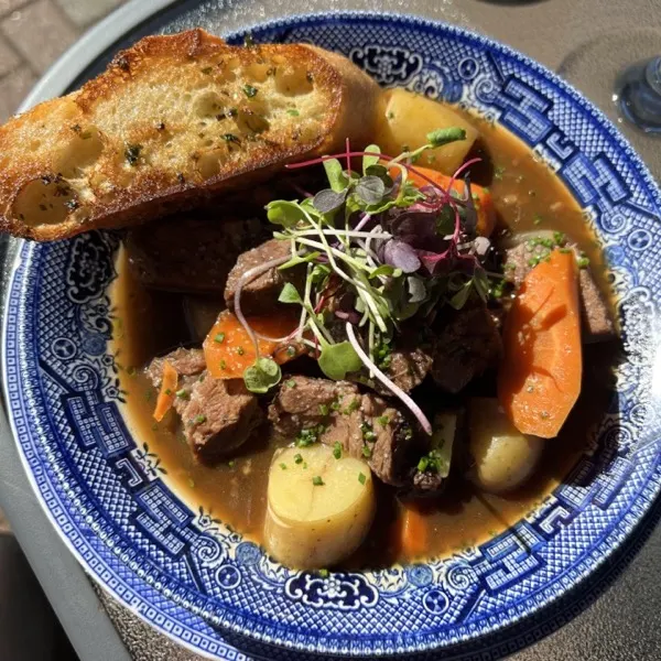 Beef stew with toasted bread in a blue willow bowl