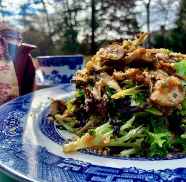 Warm mushroom salad over mixed greens on blue willow china