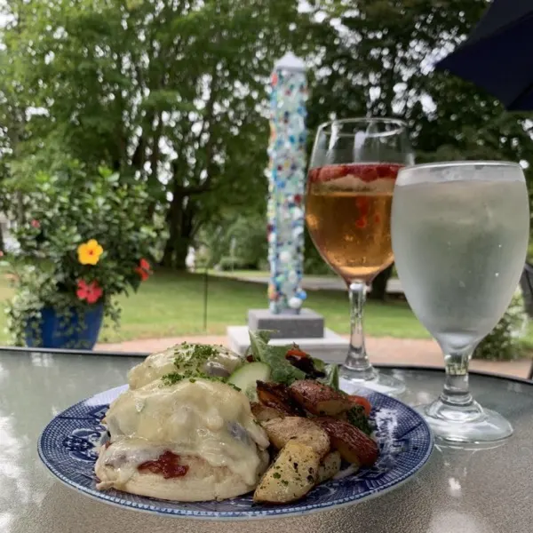 A plated entree with a glass of rosé and a glass of water on the patio