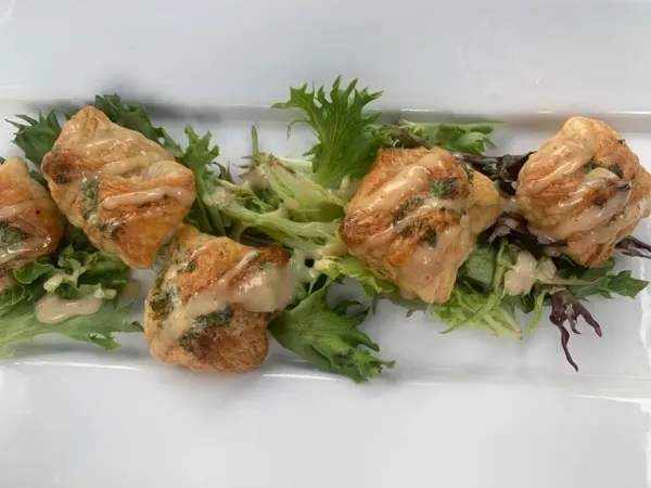 Seared salmon bites over frisée on a white platter