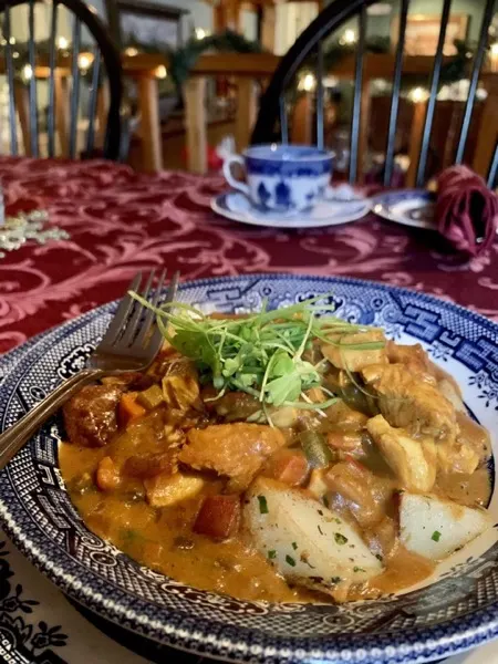 A hearty bowl of chicken and vegetables on blue willow china