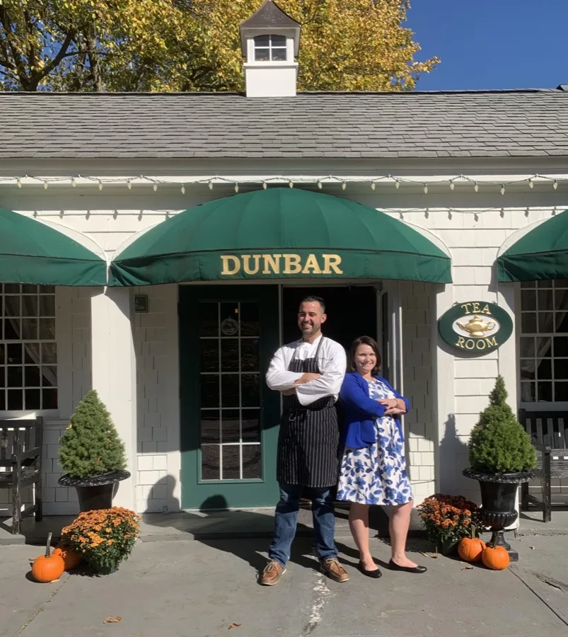 Two members of the team standing at the front door beneath the green DUNBAR awning